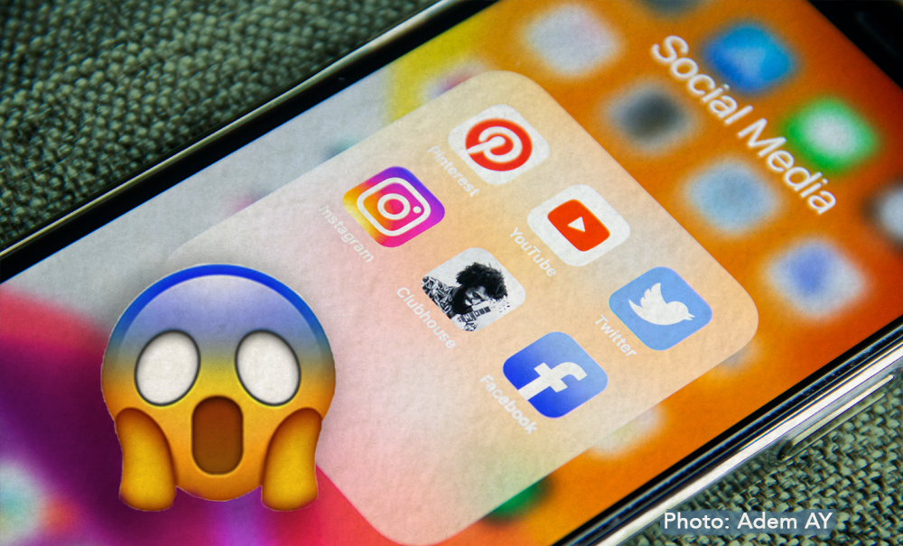 A phone with social media open with a screaming emoji overlayed.